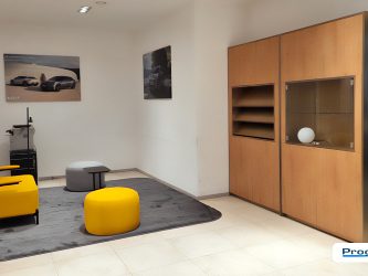 Area lounge showroom KIA Conero Car Civitanova Marche con arredi su misura e pareti effetto legno, allestimento realizzato da Progim Sign.