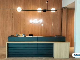 Banco reception KIA realizzato da Progim Sign, con arredi dedicati, parete rivestita effetto legno e logo KIA retroilluminato.