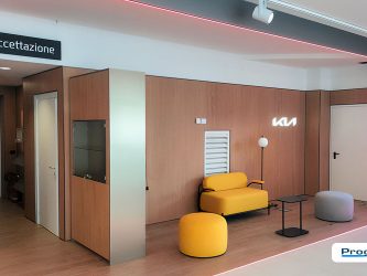 Area accettazione KIA con parete effetto legno e logo retroilluminato presso Autotorino Valmadrera, allestimento realizzato da Progim Sign.